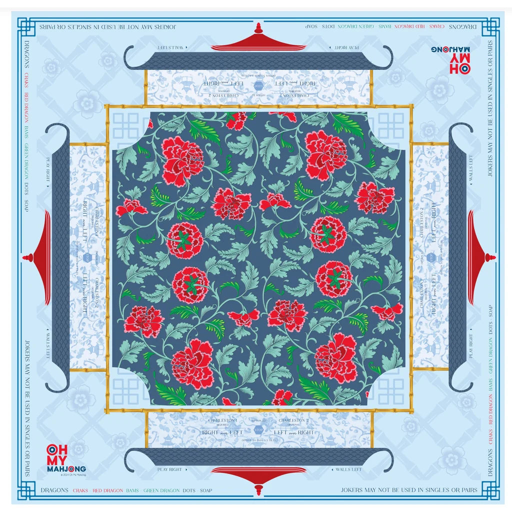 A square fabric or paper pattern sheet with a central floral print featuring red peony-like flowers and green leaves on a muted blue-gray background. The sheet is framed by decorative borders with red roof-like motifs and pale blue ornamental panels, with printed text and branding around the edges.