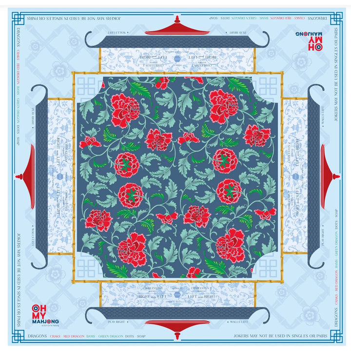 A square fabric or paper pattern sheet with a central floral print featuring red peony-like flowers and green leaves on a muted blue-gray background. The sheet is framed by decorative borders with red roof-like motifs and pale blue ornamental panels, with printed text and branding around the edges.