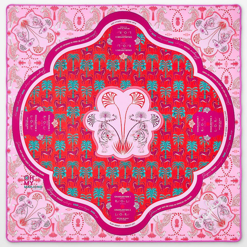 A square silk scarf laid flat, featuring a vibrant pink and red mandala design with intricate floral and botanical patterns. The central medallion is a rich red with a white border and pink floral motifs, surrounded by a wide pink border with additional decorative elements and text.
